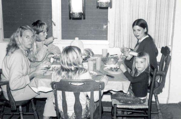 A young girl and several family members having dinner around the table.