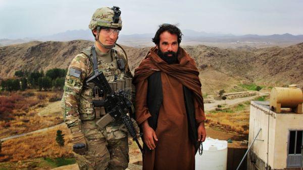 Marine Lt. Phillip Baki visits with an Afghan police officer, Abdul Karim