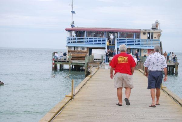 Two men walking on a pier toward a restaurant