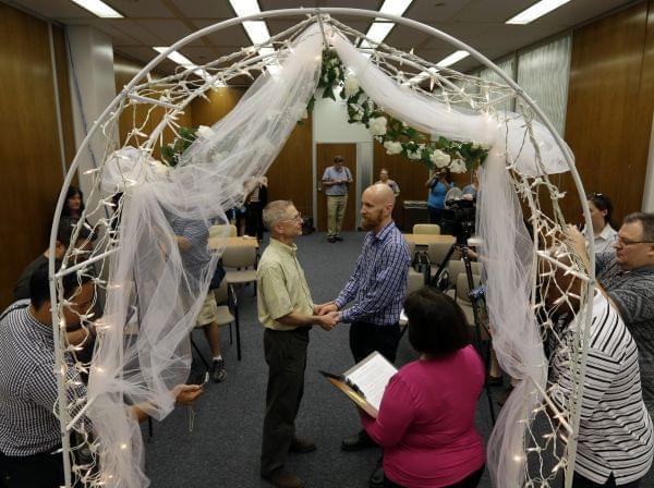 Bart Peterson, left, and Pete McNamara, center, are married by Marion County Clerk Beth White married in Indianapolis, Wednesday, June 25, 2014. A federal judge struck down Indiana's ban on same-sex marriage Wednesday in a ruling that immediatel